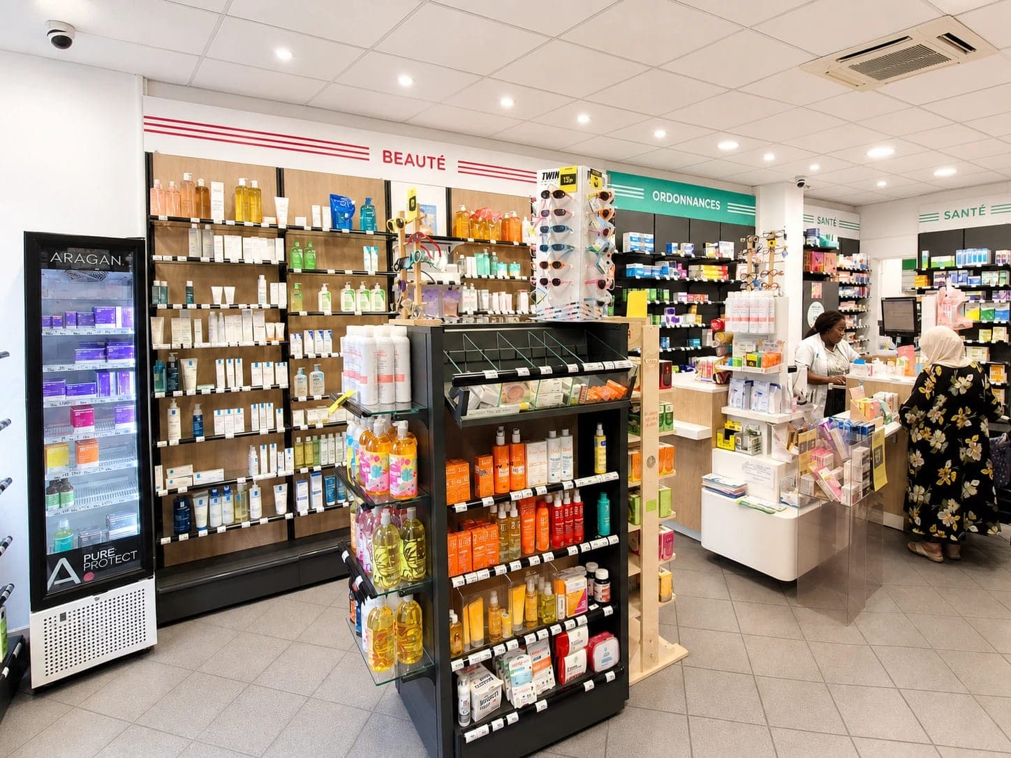 L'intérieur de la Pharmacie Sébastopol à Lille : le comptoir en bois, les rayonnages de médicaments et l'équipe au travail.